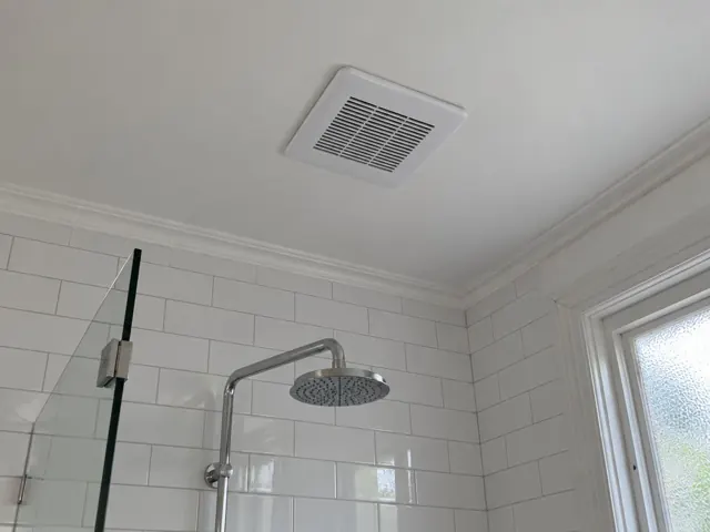 Bathroom ceiling exhaust fan above tiled shower in white tiled bathroom in Ashfield